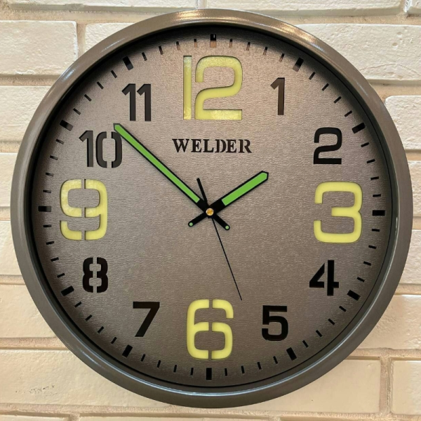 ساعت دیواری ولدر Welder مدل 609، ساعت دیواری شب نما ولدر سایز 38 با متریال صفحه تمام چوب بدنه پلاستیک، دارای فونت لاتین اعداد، دارای موتور آرامگرد درجه یک، عقربه های متفاوت شب نما، رنگ طوسی