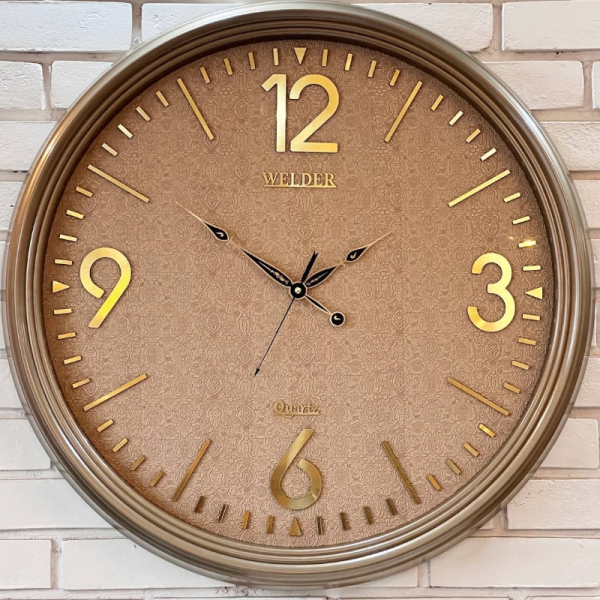ساعت دیواری ولدر Welder مدل 7010، ساعت دیواری سایز 70 با عقرب های متفاوت، دارای رنگ بندی، شماره برجسته مولتی با فونت لاتین، دارای موتور درجه یک میتسو، رنگ طوسی طلایی