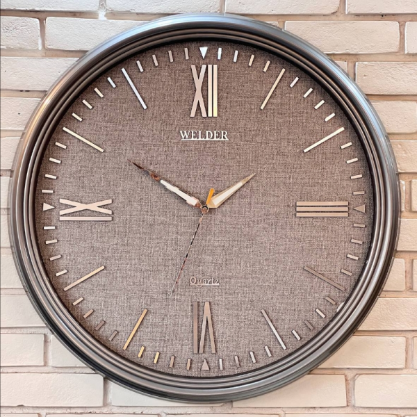 ساعت دیواری ولدر Welder مدل 7015، ساعت دیواری سایز 70 با صفحه کاغذ دیواری ترک، دارای رنگ بندی، شماره برجسته مولتی با فونت رومی، دارای موتور درجه یک میتسو، رنگ تیتانیوم